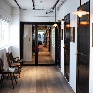 A stylish corridor decor idea featuring black doors, pendant lights, and wooden flooring