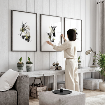 Woman arranging Japandi wall art in a bright Scandinavian living room showcasing home decor trends 2026
