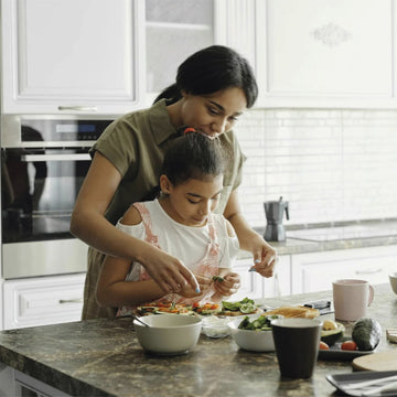A mother and daughter preparing avocado toast together in a bright modern kitchen