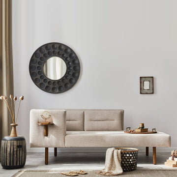 A greige sofa beneath a bold round mirror in a calm greige wall art styled living room