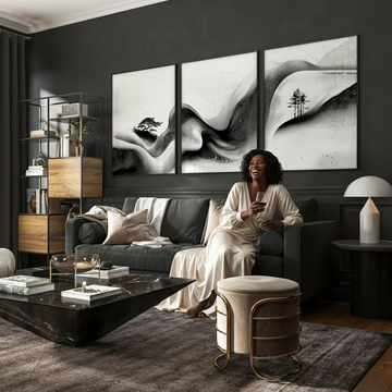 Here it is:  **Alt text:** `Black woman in cream silk dress laughing on a dark luxury sofa with black and white Asian inspired wall art prints above, showing how big wall art should be above a sofa`