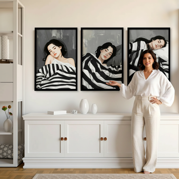 Stylish Hispanic woman in white linen gesturing at three boho women wall art prints in a bright warm living room
