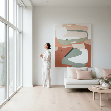 Woman admiring abstract wall art in minimalist living room with natural light and modern furnishings