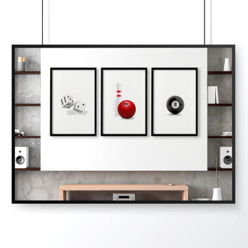 Three framed games room art prints displaying dice, bowling pin, and eight ball on white wall