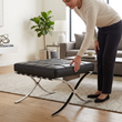 10. Barcelona black leather ottoman with a person standing beside it