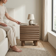 10. Clancy wooden bedside table with a person placing a book on top