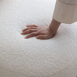 11. Evander boucle seat with a hand demonstrating cushioning