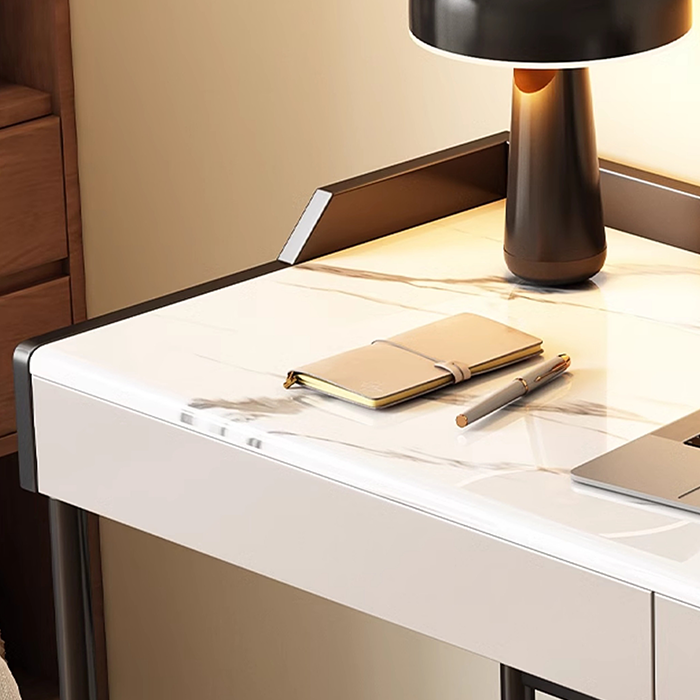 Modern desk setup with a notebook, pen, and laptop on a marble surface.