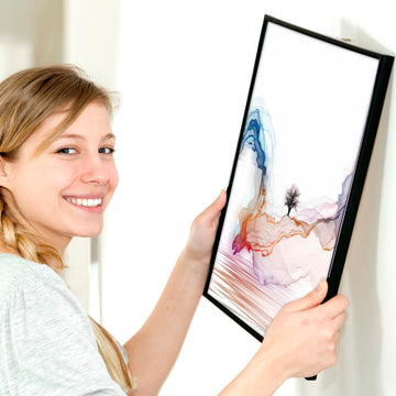 Young lady hanging a relaxing unique wall art print on the wall