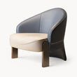 A modern barrel-style accent chair with a curved backrest upholstered in light blue and dark brown leather, a cream-colored seat cushion, and dark brown wooden legs, shown against a plain white background.
