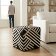 Safira black and white stripe leather pouffe in a bright living room with a person in the background