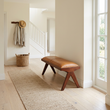 Inca tan leather and teak wood bench in a wide Scandinavian hallway view