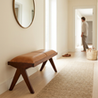 Inca tan leather and teak wood bench in a bright hallway with a person in the background
