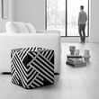 Safira black and white stripe leather pouffe in a bright living room with a person in the background